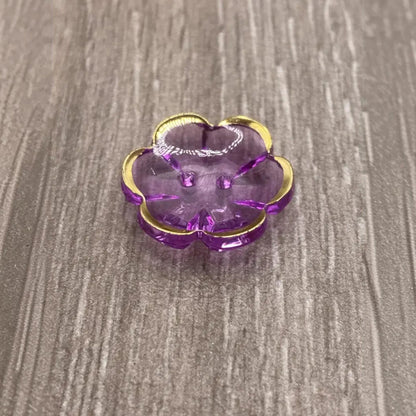Purple flower-shaped button with gold trim.