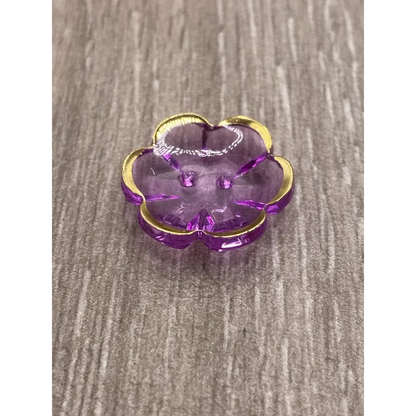 Purple flower-shaped button with gold trim.