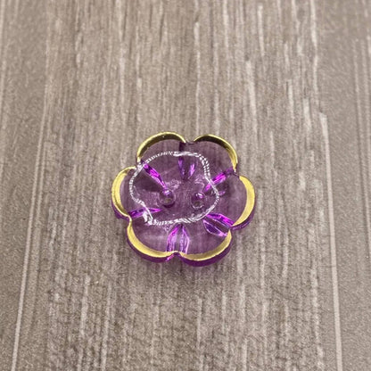 Purple flower-shaped button with gold trim.