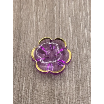 Purple flower-shaped button with gold trim.
