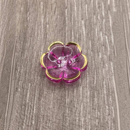 Pink and gold flower-shaped jewelry holder with jewelry.