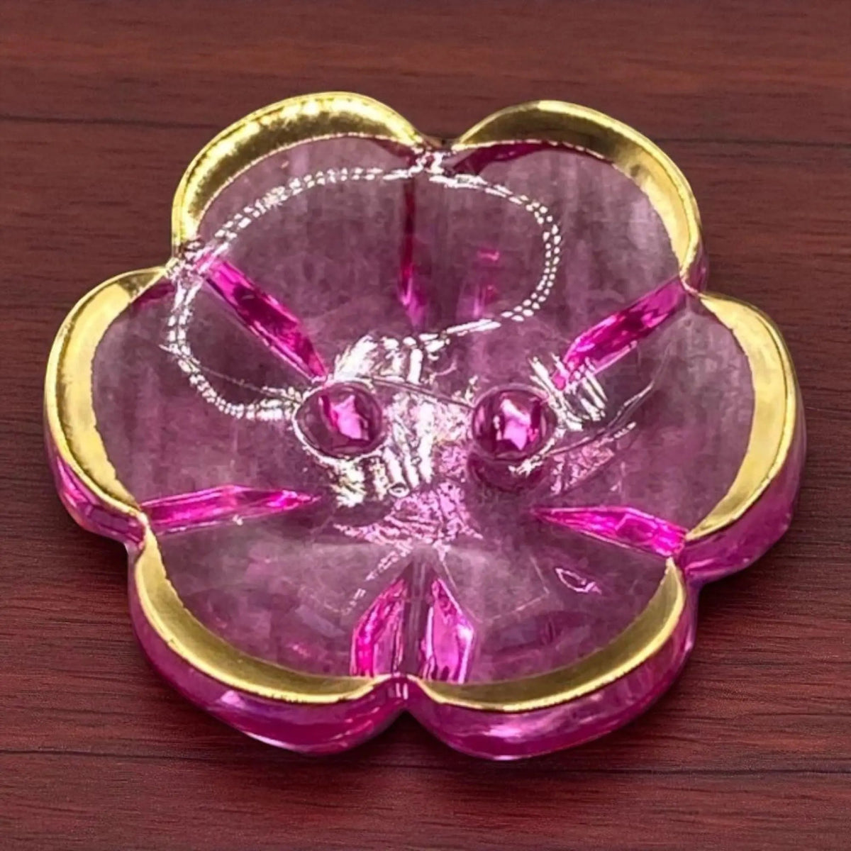 KnitForLess 13mm baby blue flower-shaped acrylic button with a gold rim and two-hole design on a wooden surface