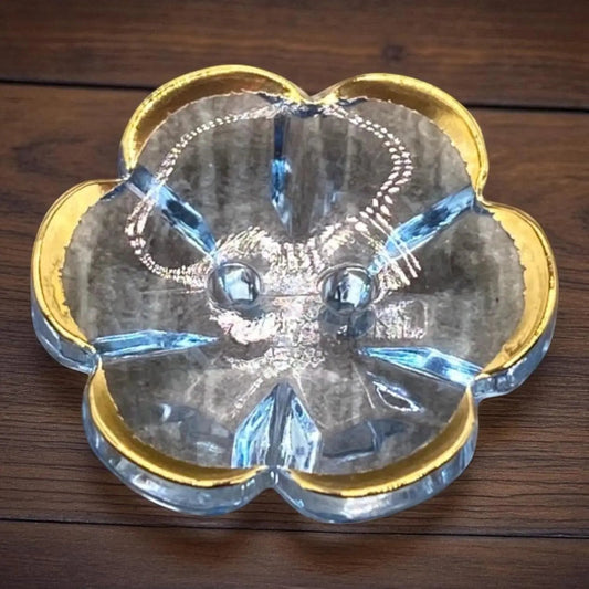 KnitForLess 13mm baby blue flower-shaped acrylic button with a gold rim and 2-hole design on a wooden surface