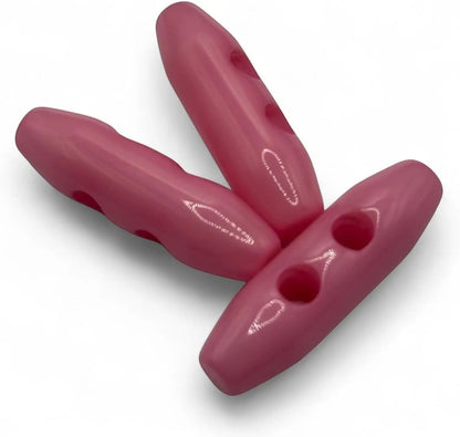 KnitForLess 38mm baby pink plastic toggle buttons with a 2-hole design for sewing and outerwear projects.