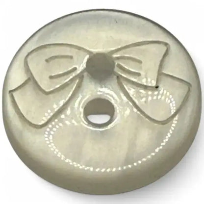 Round, pearlescent button with a bow design.
