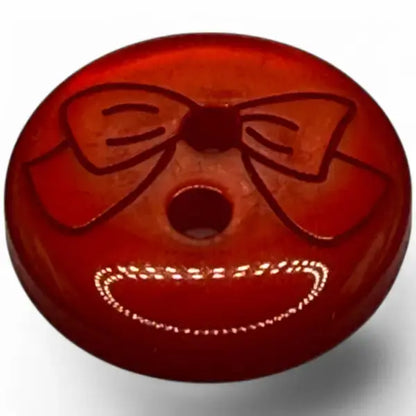 Red button with a bow and dotted smile.
