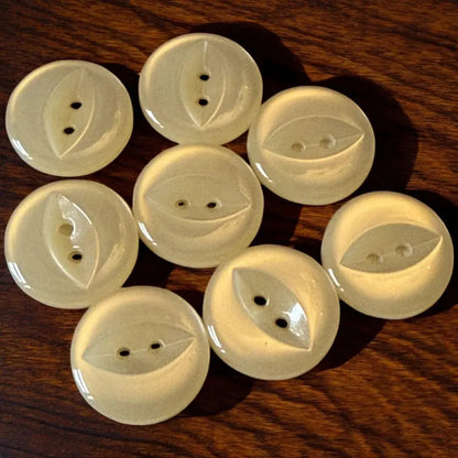 Eight round, pale yellow buttons with leaf-shaped designs and two holes.
