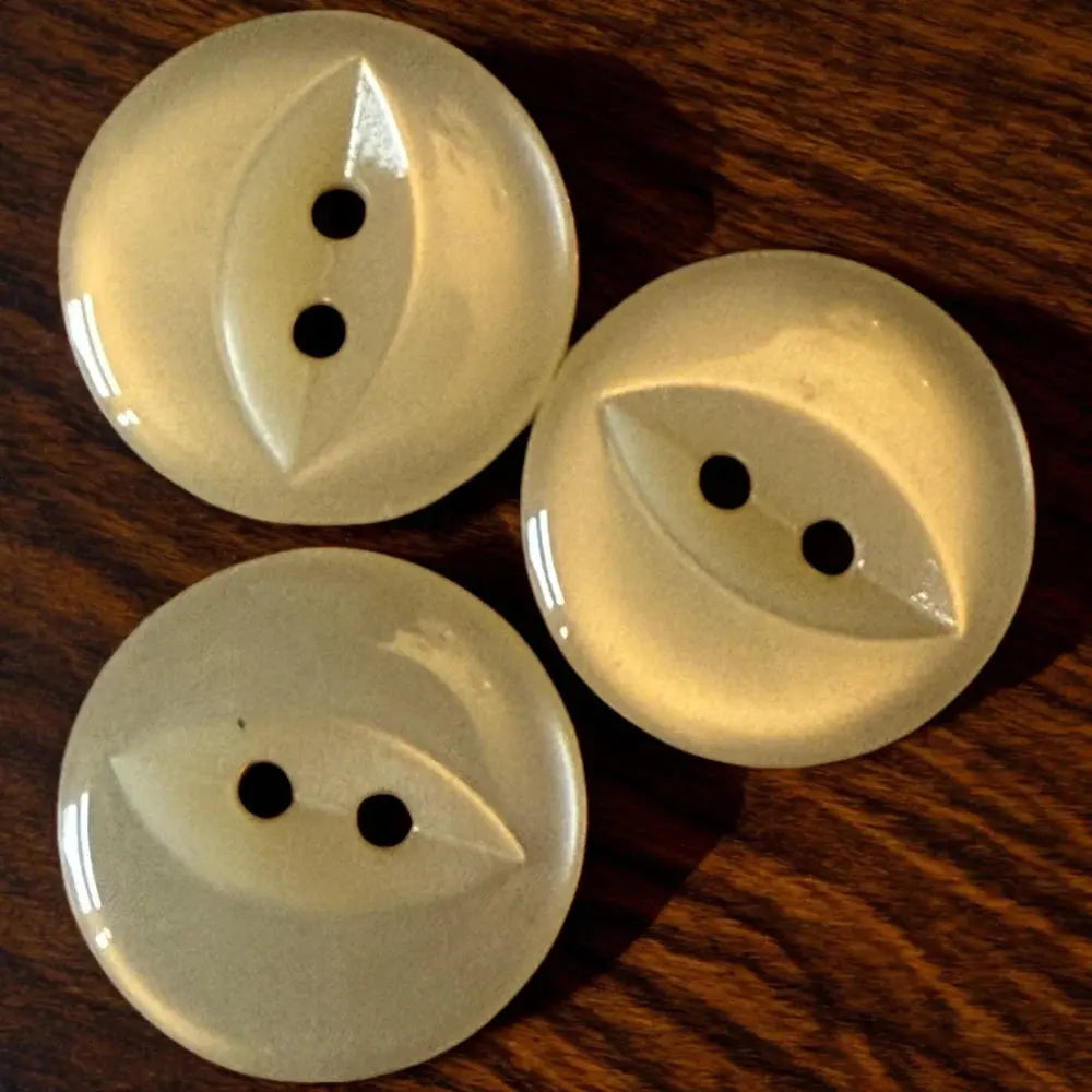 Three round, pale yellow buttons with a leaf-shaped design and two holes.