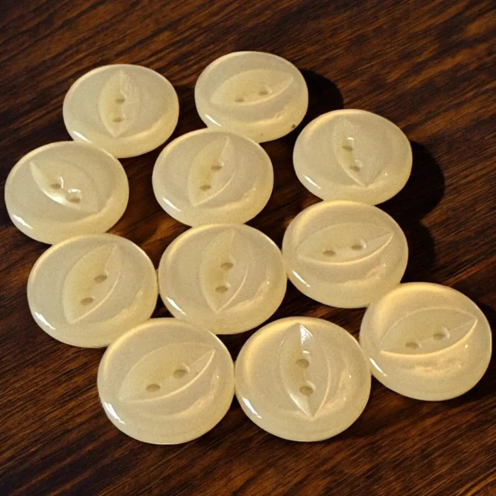 Collection of pale yellow, round buttons with leaf design.