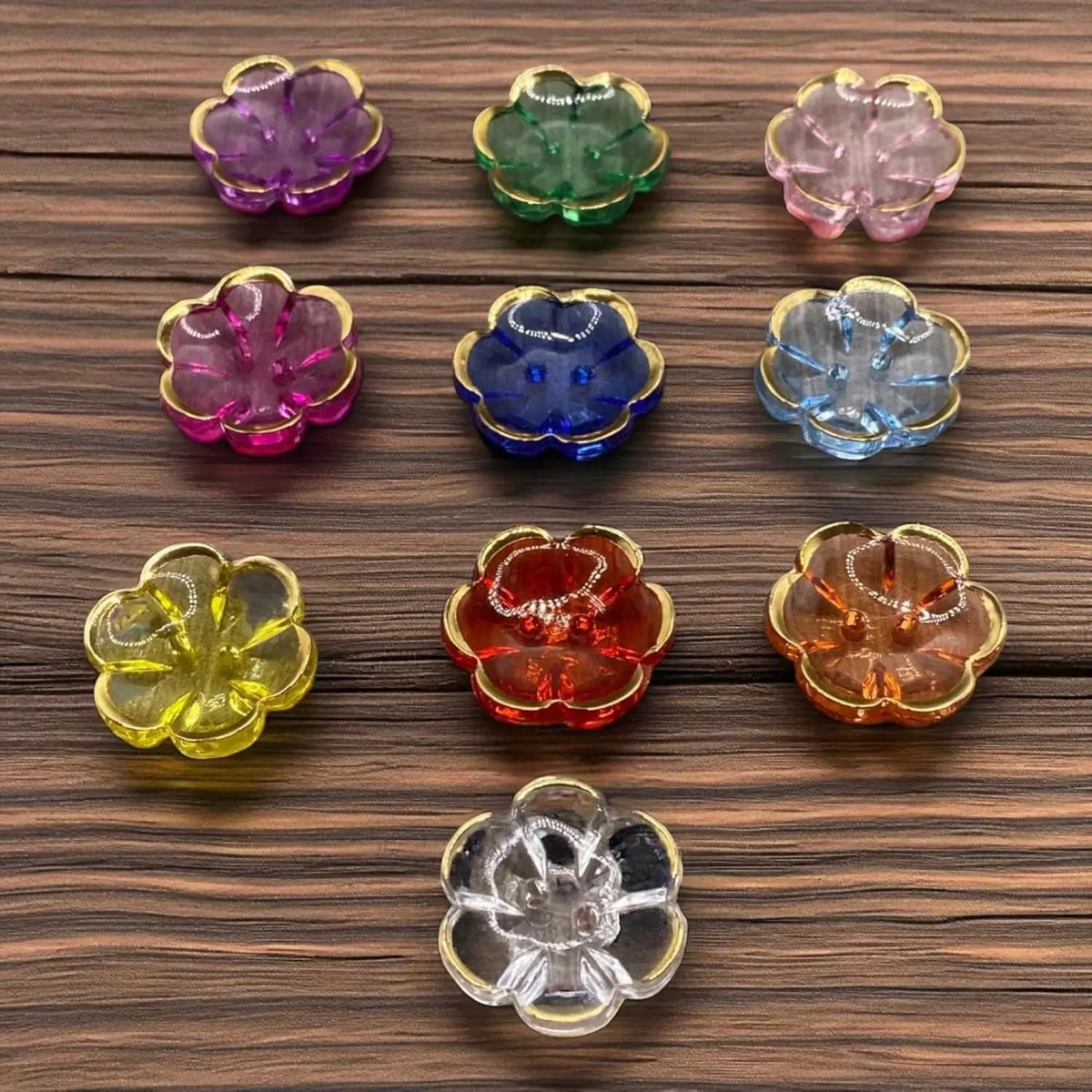 KnitForLess 13mm flower-shaped acrylic buttons with gold rims in various vibrant colors on a wooden surface