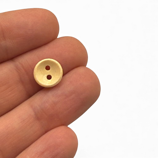 KnitForLess light brown 10mm wooden button with two holes held between fingers for scale