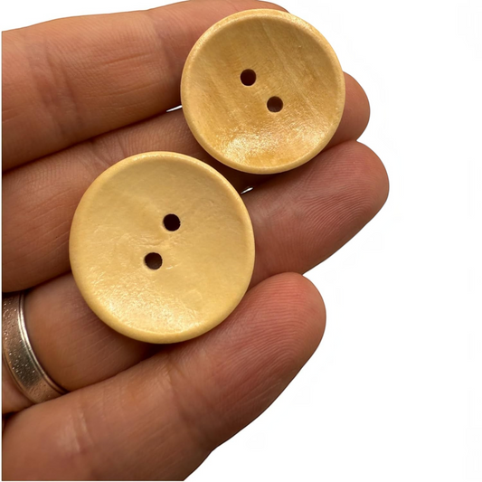 KnitForLess light brown 25mm wooden buttons with a two-hole design held in a hand for scale