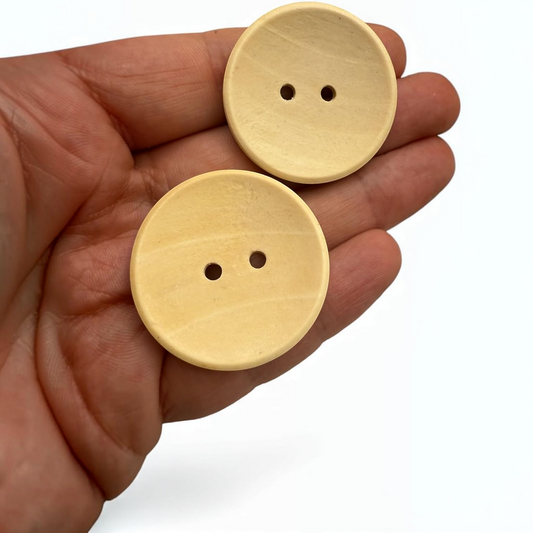 KnitForLess light brown wooden buttons, 35mm round 2-hole design held in a palm for scale