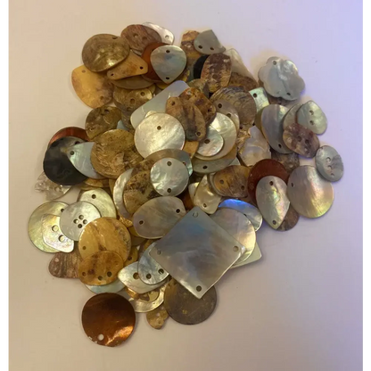 Pile of iridescent shell beads with holes.