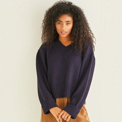KnitForLess vintage boxy navy blue V-neck sweater with ribbed neckline and hem worn by a woman with curly hair.