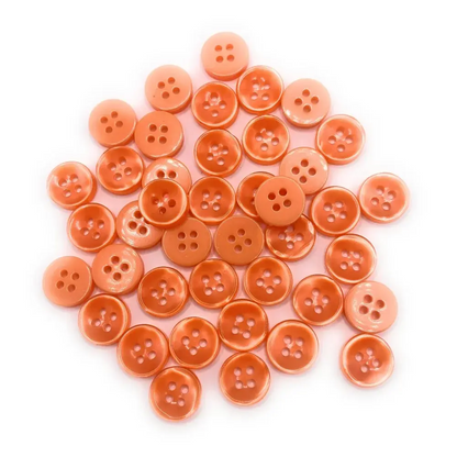 Pile of peach-colored sewing buttons.