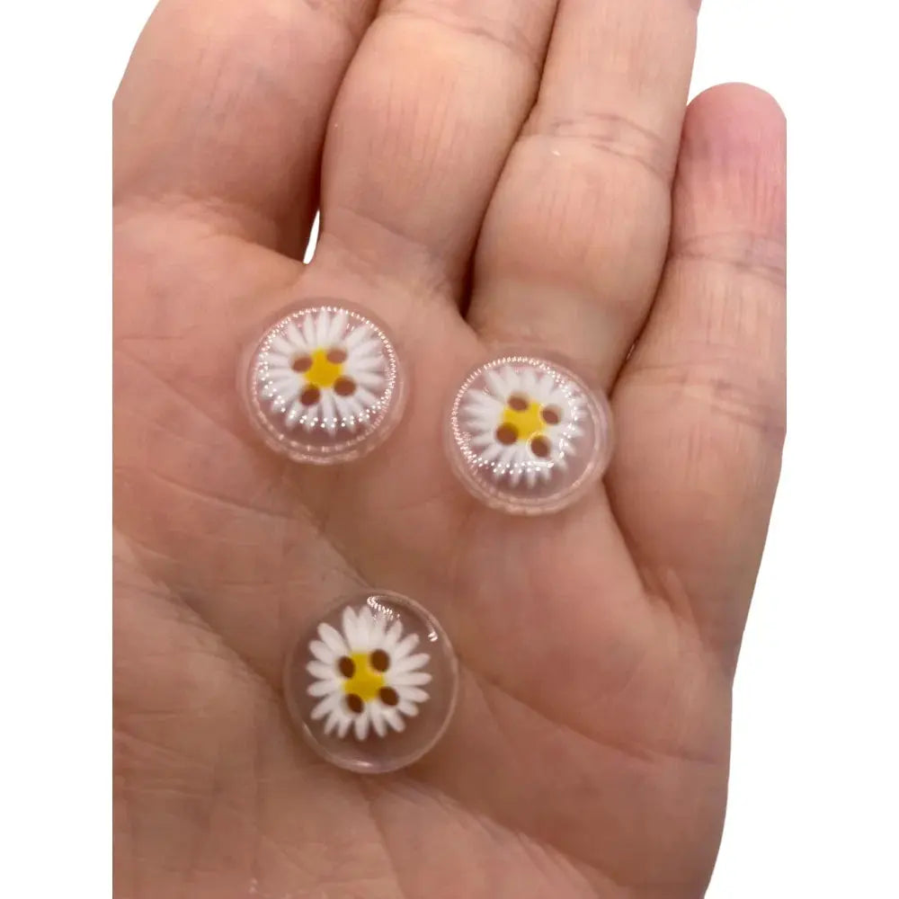 Three daisy-themed glass cabochons.