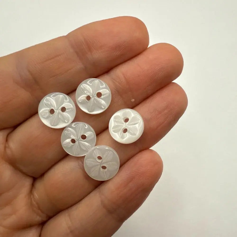Hand holding flower-patterned buttons.