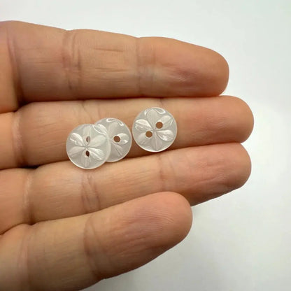 Three white flower-patterned buttons.
