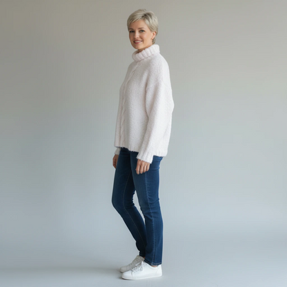 Woman wearing a KnitForLess vintage-style cream turtleneck sweater with blue jeans and white sneakers